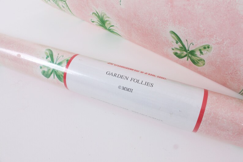 May include: A roll of pink wallpaper with a green butterfly pattern. The label reads "Garden Follies &copy;MMII".