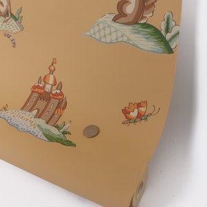 Puede incluir: Un rollo de papel tapiz amarillo con un patr&oacute;n repetitivo de un castillo, una ardilla, una mariposa y un animal peque&ntilde;o. El papel tapiz tiene un aspecto y una sensaci&oacute;n vintage.