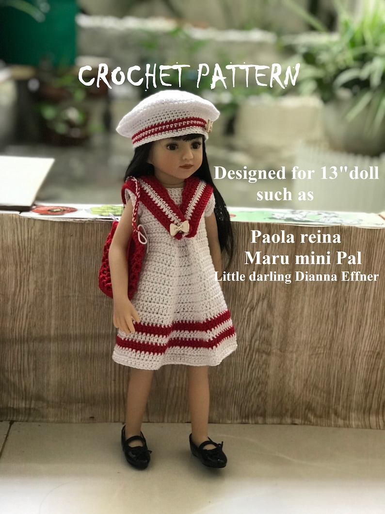 May include: Crochet pattern for a 13-inch doll, featuring a white dress with red stripes and a white sailor hat. The doll is wearing black shoes. The pattern is designed for dolls such as Paola Reina, Maru mini Pal, and Little darling Dianna Effner.