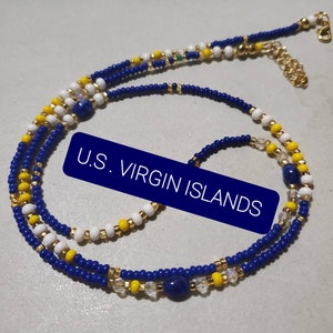 May include: A blue, white, and yellow beaded necklace with gold accents and a blue stone charm. The necklace is layered and has a clasp closure. The text "U.S. VIRGIN ISLANDS" is visible in the image.