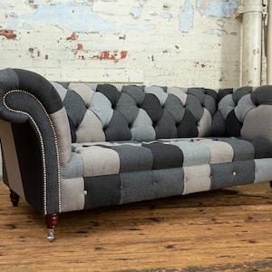 May include: A patchwork sofa with a tufted back and rolled arms. The sofa is upholstered in a variety of shades of grey and black fabric.