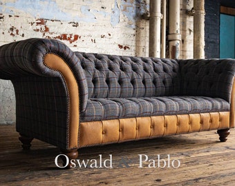 May include: A gray and brown plaid sofa with a tufted back and leather trim. The sofa has a wooden frame and legs. The sofa is sitting on a wooden floor. The text "Oswald & Pablo" is visible in the lower right corner of the image.