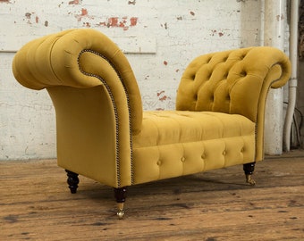 May include: A mustard yellow velvet tufted bench with wooden legs and brass casters. The bench has a curved back and arms.