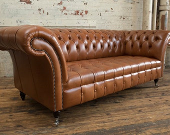 May include: A brown leather chesterfield sofa with button tufting and rolled arms. The sofa has a traditional design and is upholstered in a rich brown leather.