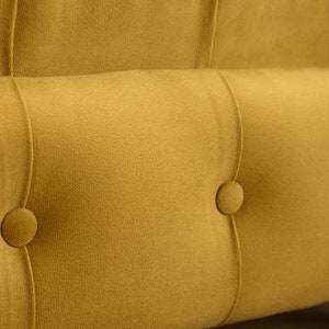Puede incluir: Primer plano de un sof&aacute; amarillo mostaza capiton&eacute; con detalles de botones. El sof&aacute; tiene un tejido suave y mullido y un dise&ntilde;o cl&aacute;sico.