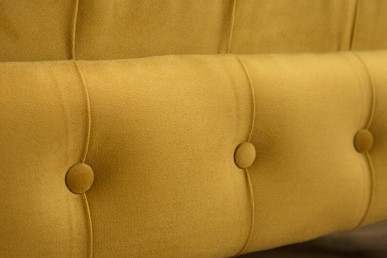 Puede incluir: Primer plano de un sof&aacute; amarillo mostaza capiton&eacute; con detalles de botones. El sof&aacute; tiene un tejido suave y mullido y un dise&ntilde;o cl&aacute;sico.
