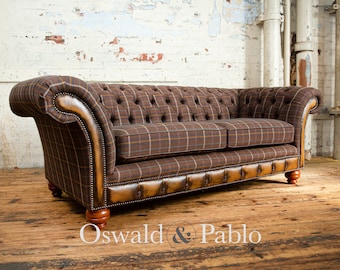 May include: A brown and tan plaid sofa with a tufted back and leather trim. The sofa has wooden legs and is sitting on a wooden floor. The text "Oswald & Pablo" is visible in the bottom right corner of the image.
