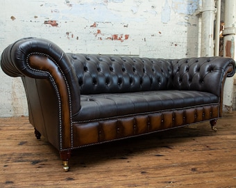 May include: A brown leather Chesterfield sofa with button tufting and rolled arms. The sofa has a distressed leather finish and wooden legs.