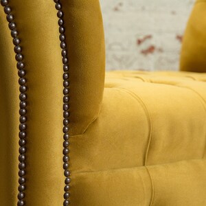 Puede incluir: Primer plano de un sill&oacute;n de terciopelo amarillo mostaza con tapicer&iacute;a capiton&eacute; y ribetes de cuentas marrones oscuras.