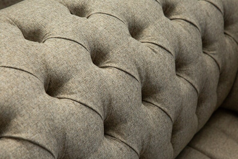 May include: Close-up of a brown tufted fabric with a buttoned design. The fabric has a textured, woven appearance.