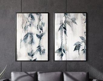 Może przedstawiać: Dwa oprawione abstrakcyjne wydruki artystyczne o tematyce botanicznej. Grafika charakteryzuje się stylem akwarelowym z odcieniami niebieskiego, szarego i białego. Wydruki są wyświetlane nad czarną skórzaną sofą, z dwoma małymi drewnianymi stolikami i dekoracyjnymi wazonami.