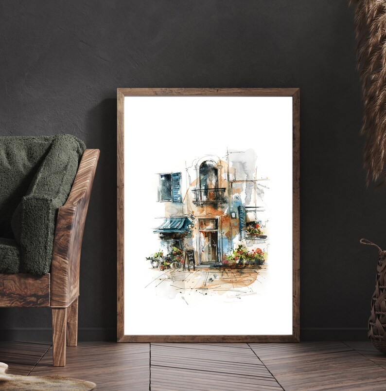 Op de afbeelding: Aquarel schilderij van een Europees gebouw met een balkon, blauwe luiken en een kleine luifel. Het kunstwerk is ingelijst in een lichtbruine houten lijst en wordt tentoongesteld op een donkere houten vloer. Het kleurenpalet omvat tinten bruin, blauw en oranje.