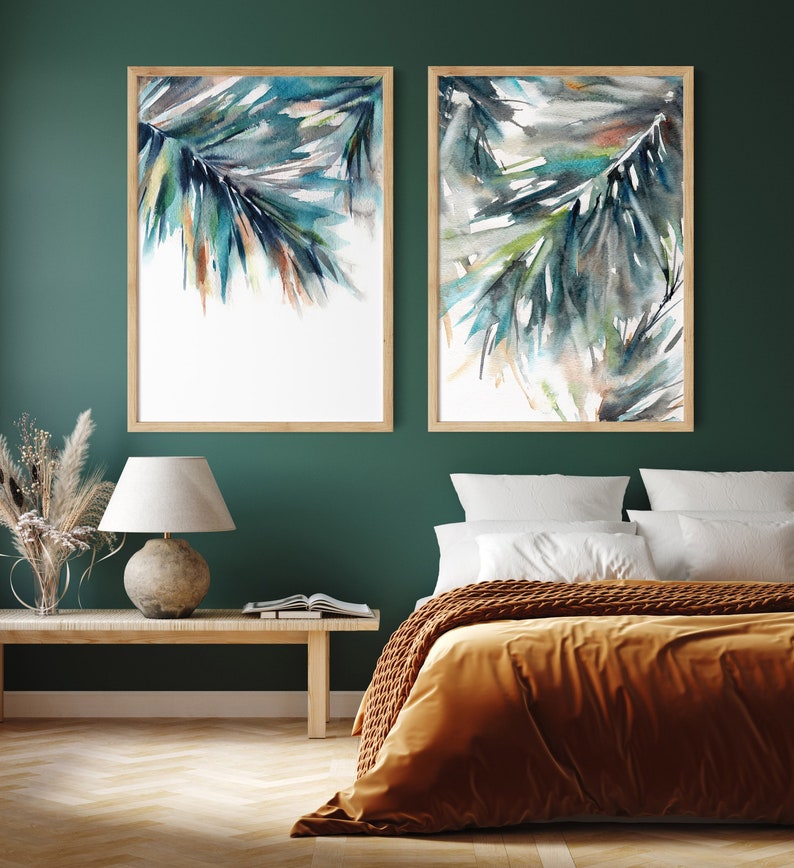 Puede incluir: Dos pinturas de acuarela enmarcadas de palmas abstractas en tonos turquesa, azul y marr&oacute;n. La obra de arte se exhibe en una pared verde oscuro sobre una cama con una manta color mostaza. Los marcos son de madera clara.