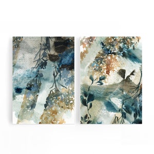 May include: Two abstract watercolor paintings. The artwork features a blend of blue, brown, and beige hues, with botanical elements. The paintings have a textured appearance, with visible brushstrokes and layered colors, creating a sense of depth and movement.