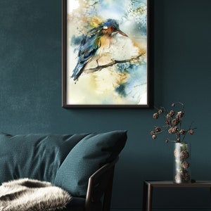 May include: Watercolor painting of a bird perched on a branch, framed in a black frame. The bird features blue, orange, and brown hues. The background has soft watercolor washes of blue, yellow, and white. The artwork is displayed on a dark teal wall.