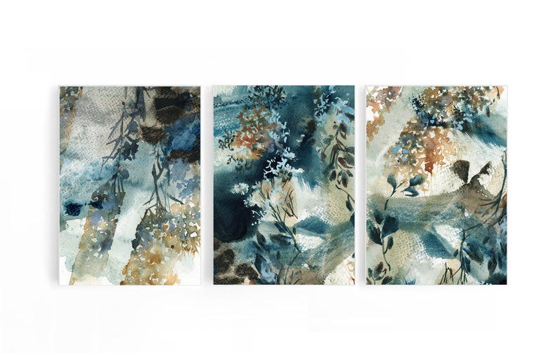 K&ouml;nnte beinhalten: Set aus drei abstrakten Aquarellgem&auml;lden. Jedes St&uuml;ck zeigt eine Mischung aus Blau-, Braun- und Beiget&ouml;nen mit botanisch inspirierten Formen und Texturen. Das Kunstwerk ist auf wei&szlig;em Hintergrund montiert.
