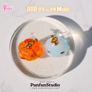 May include: Two resin molds for making earrings. One mold is orange and shaped like a pumpkin. The other mold is light blue and shaped like a whale. The molds are on a white background with glitter.