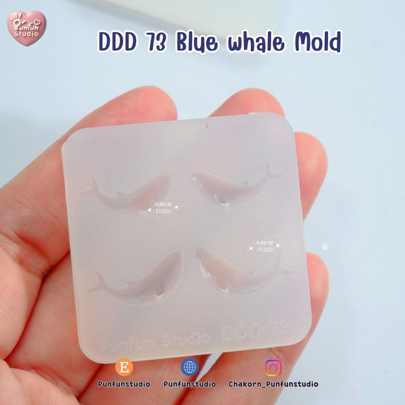 May include: A clear silicone mold with four blue whale shapes. The mold has the text "DDD 73 Blue whale Mold" and "Punfun Studio" printed on it. The mold is held in a hand.