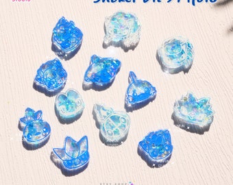 May include: A set of 10 clear resin shaker molds with blue outlines. The molds are shaped like various cartoon characters, including a heart, a star, a rocket, and a ladybug. The molds are designed for use with resin and glitter to create shaker charms.