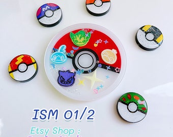 May include: A white and red Pokeball with a clear resin top. The Pokeball is decorated with glitter, stars, and small Pokemon characters. The Pokeball is surrounded by six smaller Pokeballs, each with a different Pokemon character.