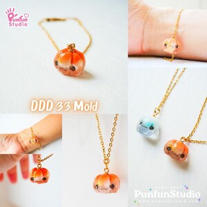 May include: A gold chain necklace with a small orange pumpkin charm. The pumpkin has a cute face with eyes, a nose, and a smile. The necklace is on a white background. DDD 33 Mold.
