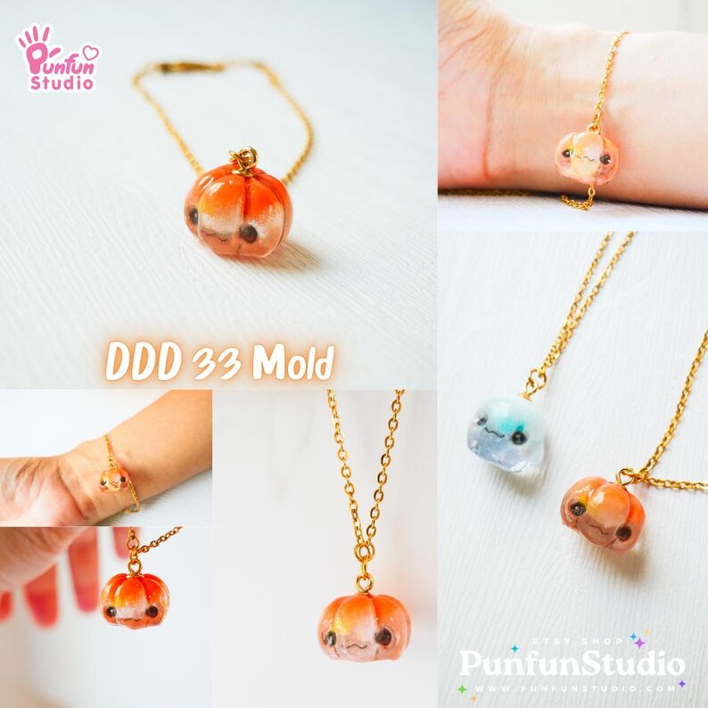 May include: A gold chain necklace with a small orange pumpkin charm. The pumpkin has a cute face with eyes, a nose, and a smile. The necklace is on a white background. DDD 33 Mold.