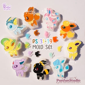 以下が含まれることがあります： イーブイ、ブースター、シャワーズ、サンダース、エーフィ、ブラッキー、リーフィア、グレイシア、ニンフィアなど、さまざまなポケモンのキャラクターをフィーチャーした9個のシリコンモールドセット。モールドは白で、クリアで光沢のある仕上げになっています。テキスト「PS 31-39 MOLD Set」は、白地に虹色で印刷されています。