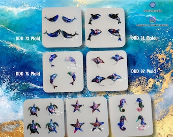 May include: A collection of silicone molds featuring marine life designs, including dolphins, sea turtles, starfish, and seahorses. The molds are arranged on a blue and gold background, with the text "DDD 73-79 Mold" at the top.