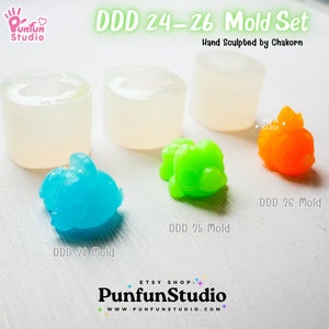 May include: A set of three silicone molds for making small animal figurines. The molds are clear and show the details of the animal shapes. The molds are labeled DDD 24, DDD 25, and DDD 26. The image also shows three finished figurines made with the molds, in blue, green, and orange.