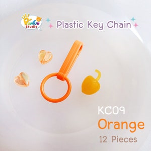 May include: Orange plastic key chain with a heart-shaped charm and a small orange charm. The keychain is labeled "KC09 Orange 12 Pieces".