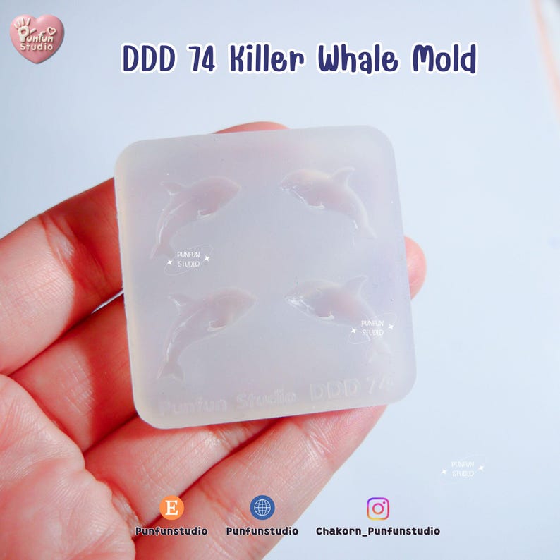 May include: A clear silicone mold with four killer whale designs. The text "DDD 74 Killer Whale Mold" is printed at the top. The mold is held in a hand.