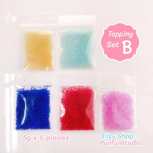 May include: Set of five 5-gram bags of colourful, round, clear, and opaque beads. The beads are in separate bags, labelled "Topping Set B".