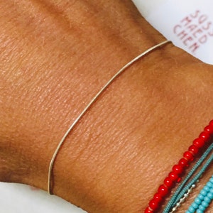 May include: A silver chain bracelet on a person's wrist. The bracelet is thin and delicate.