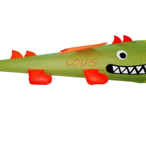 Könnte beinhalten: Grüner und orangefarbener Filz-Drachen-Kegel mit weißen Punkten und dem Namen "Louis" auf der Seite bestickt.