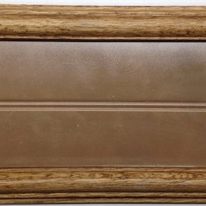May include: A wooden frame with a brown background and two small holes. The frame is made of a light brown wood with a darker brown stain.