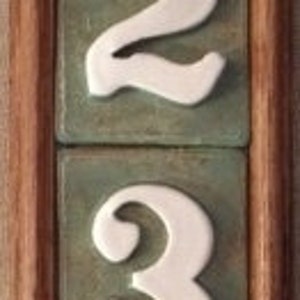 May include: A wooden frame with four white ceramic tiles, each with a number, 1, 2, 3, and 4, on a green background.
