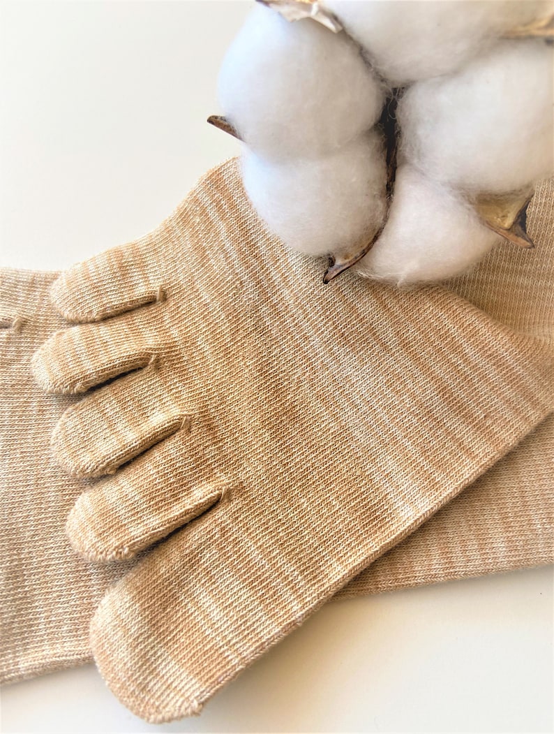 May include: A pair of beige toe socks with five individual toe compartments. The socks are made of a soft, breathable fabric and are designed to provide comfort and support.