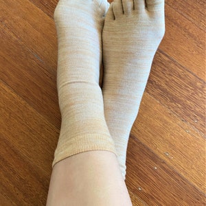 May include: A pair of beige toe socks with a subtle marbled pattern. The socks are made of a soft, breathable fabric and are perfect for everyday wear.