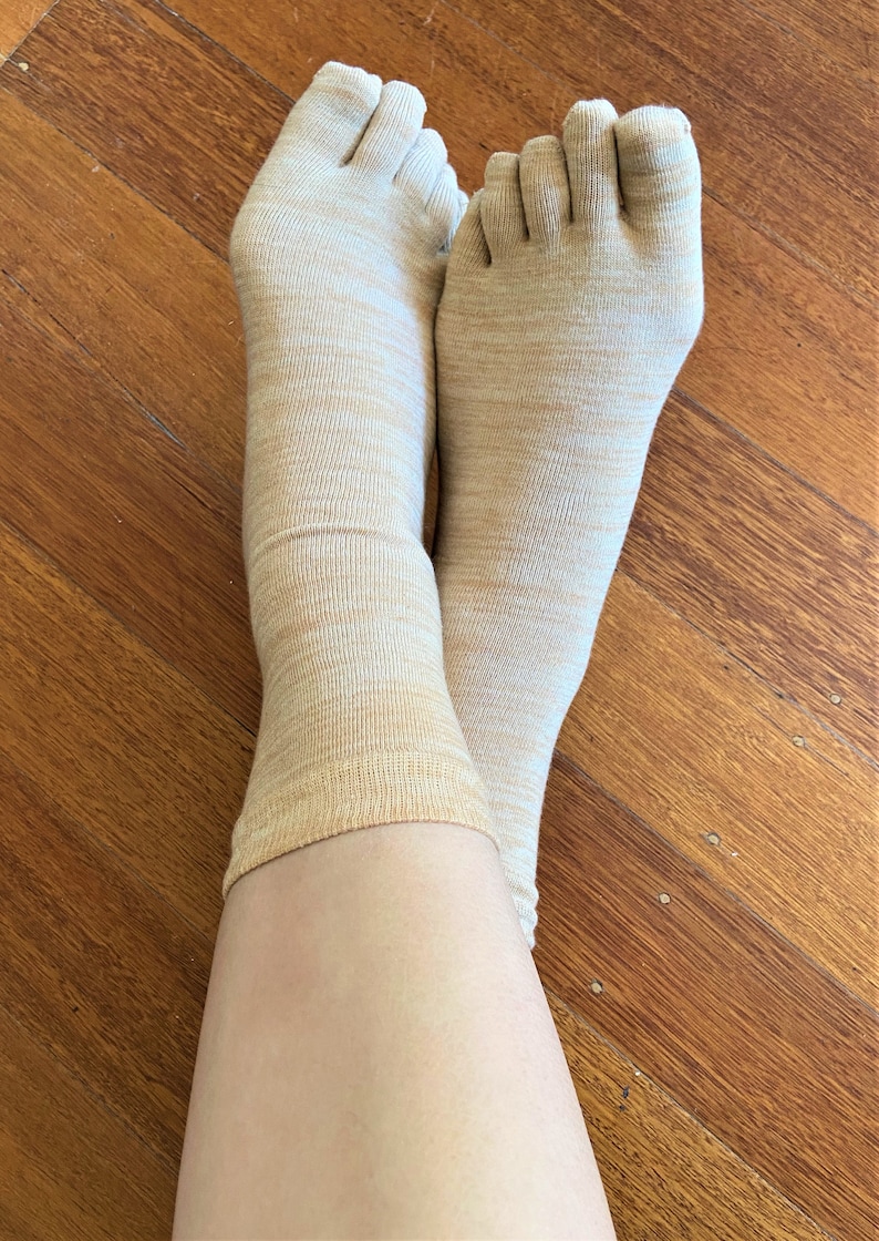 May include: A pair of beige toe socks with a subtle marbled pattern. The socks are made of a soft, breathable fabric and are perfect for everyday wear.