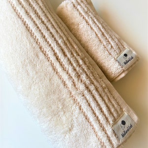 May include: Two beige towels with a textured pattern and a black and white logo that says "Naturell Lab" on each towel.