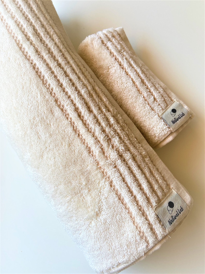 May include: Two beige towels with a textured pattern and a black and white logo that says "Naturell Lab" on each towel.