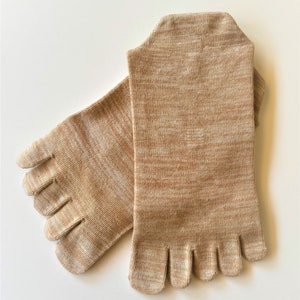 May include: A pair of beige toe socks with a textured knit pattern. The socks have five separate toe compartments.