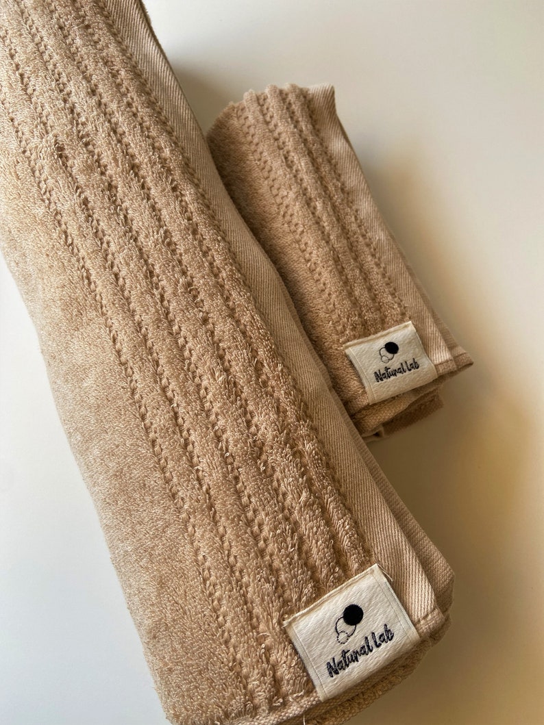 May include: Two brown towels with a white tag that says "Natural Lab" on each. The towels are rolled up and have a textured surface.