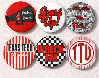 May include: A collection of six round buttons with various designs and text. The buttons feature phrases like "Raider Power," "Guns Up!," and "Wreck 'em Tech!" in red and white. Other buttons display "Texas Tech Red Raiders" and a checkered pattern.