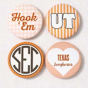 May include: Four round buttons with orange and white designs. One button has the text "Hook 'Em" on a gingham background. Another has "UT" on orange stripes. The third has "SEC" in a circle. The last has a heart with "TEXAS Longhorns".