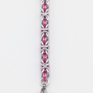 May include: A silver and pink chain bracelet with a lobster clasp closure.