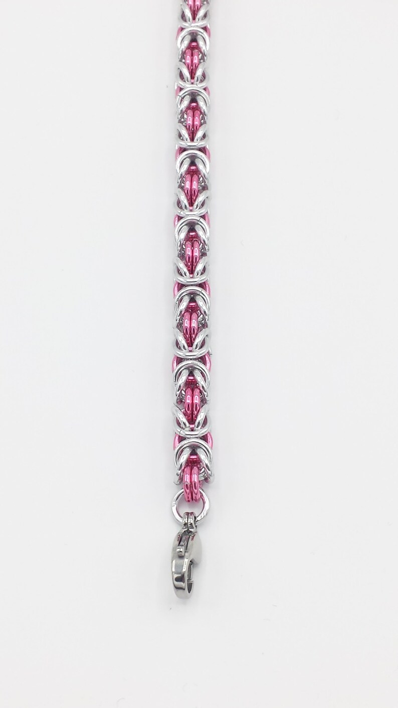 May include: A silver and pink chain bracelet with a lobster clasp closure.