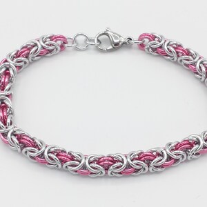 May include: A silver and pink chain bracelet with a lobster clasp closure.