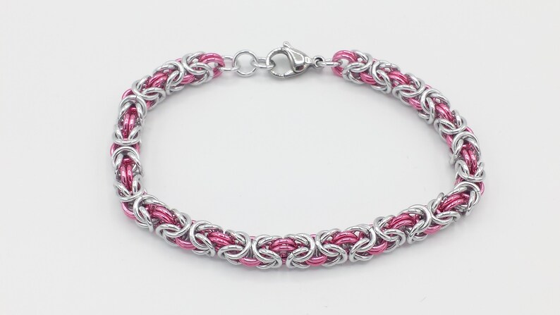May include: A silver and pink chain bracelet with a lobster clasp closure.