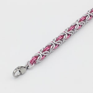 May include: A silver and pink chain bracelet with a lobster clasp closure.